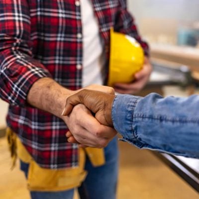 two men shaking hands in a construction area, symbolizing partnership and collaboration in a building project