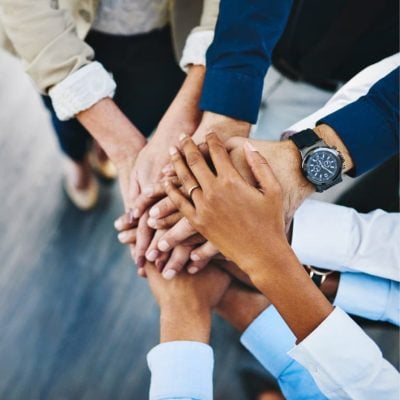 a diverse group of business professionals stacking their hands together in a show of teamwork and collaboration