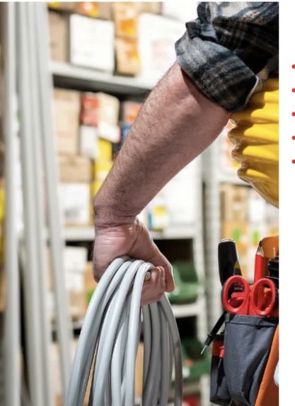 Worker carrying electrical cable in a warehouse setting